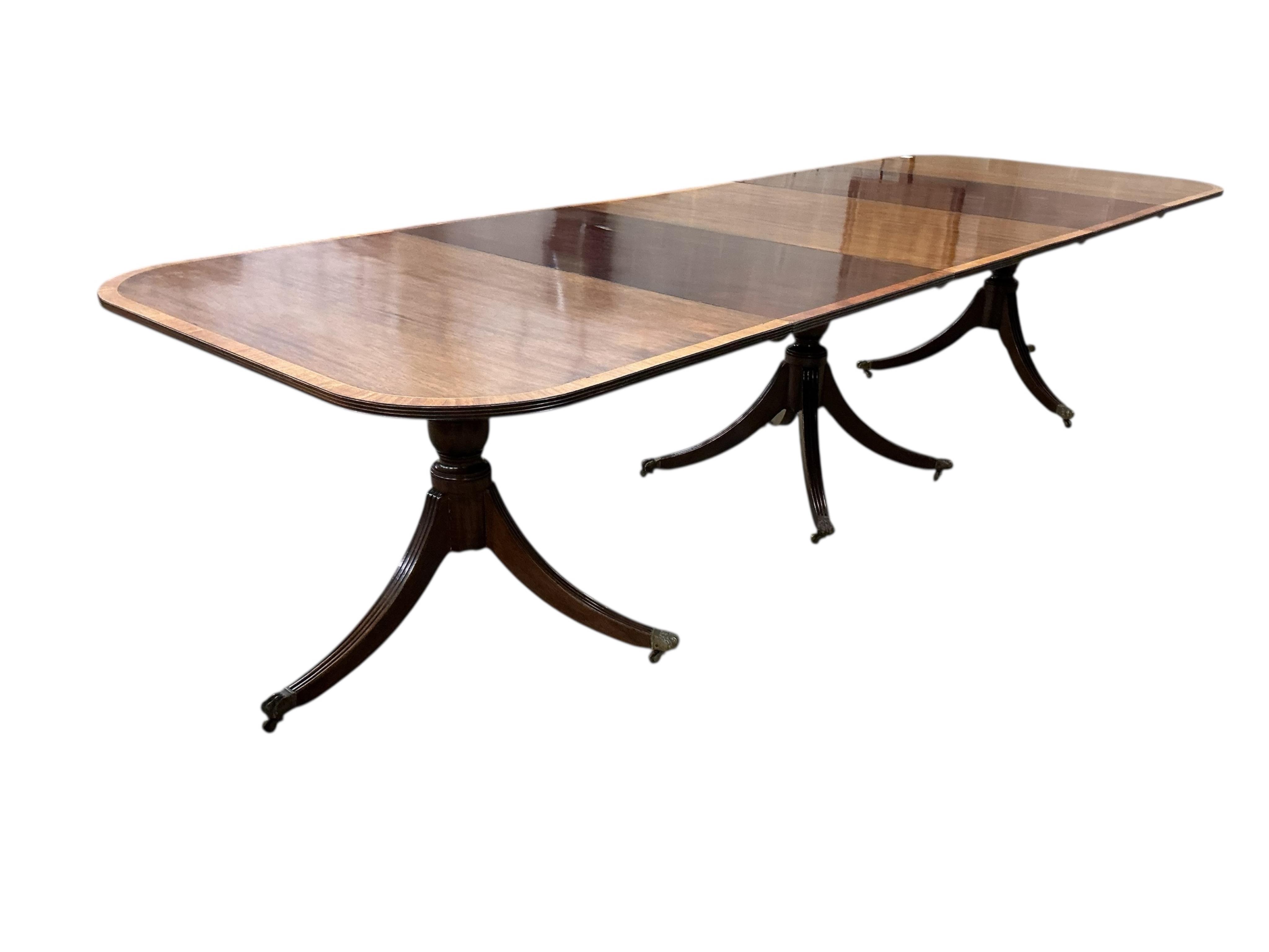 A Regency style mahogany and satinwood banded three pillar dining table, width 320cm extended, two spare leaves, depth 114cm, height 74cm